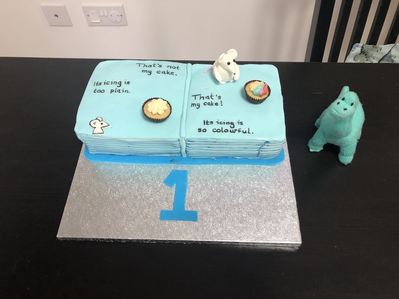 Blue book-themed first birthday cake with fondant details